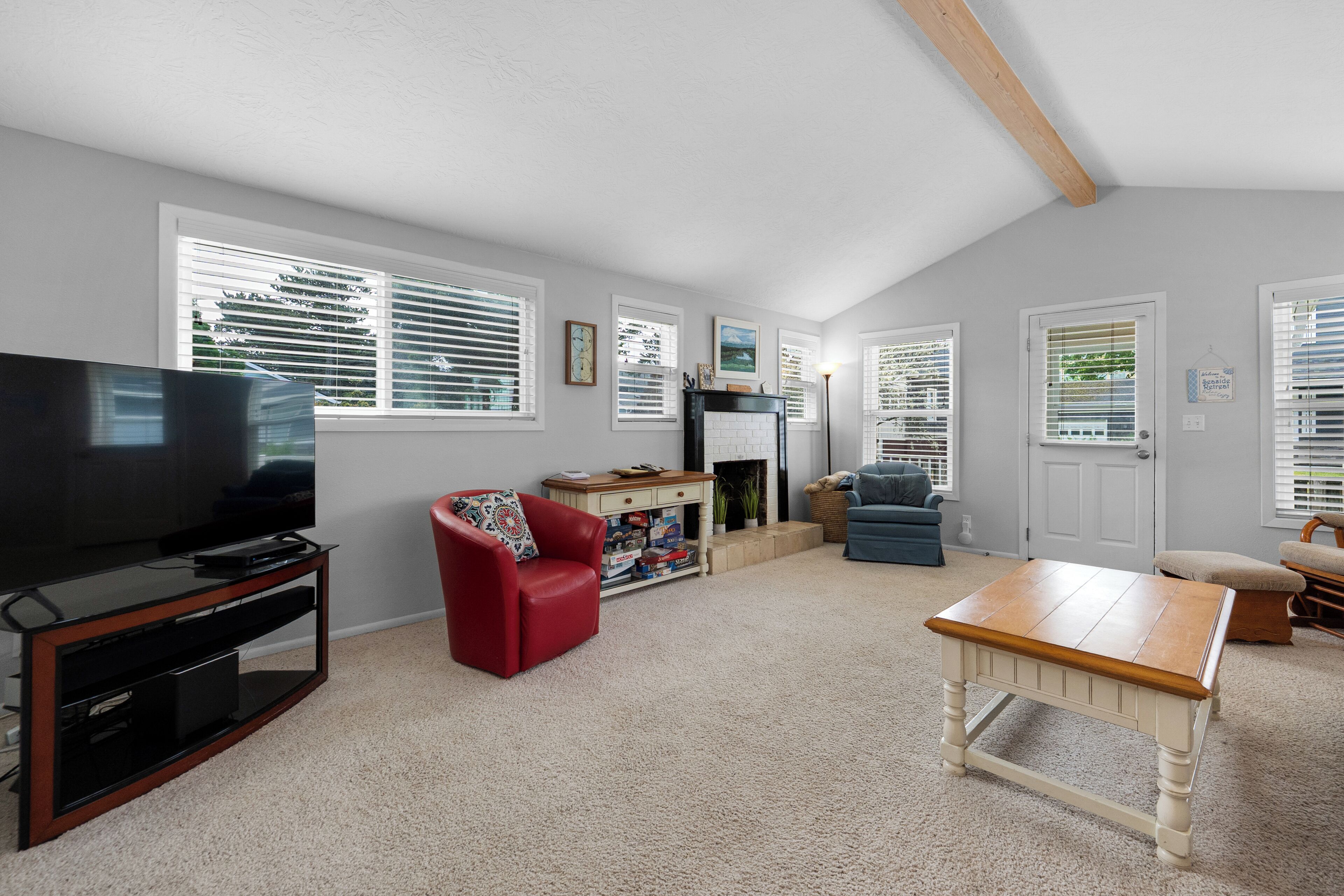 A living room with a TV, red chair, wooden table, and a fireplace.