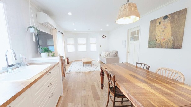 A spacious kitchen with a wooden dining table, white cabinetry, and a hanging light fixture.