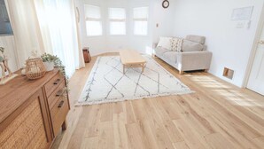 A bright living room with a wooden floor, a sofa, a coffee table, and a rug.