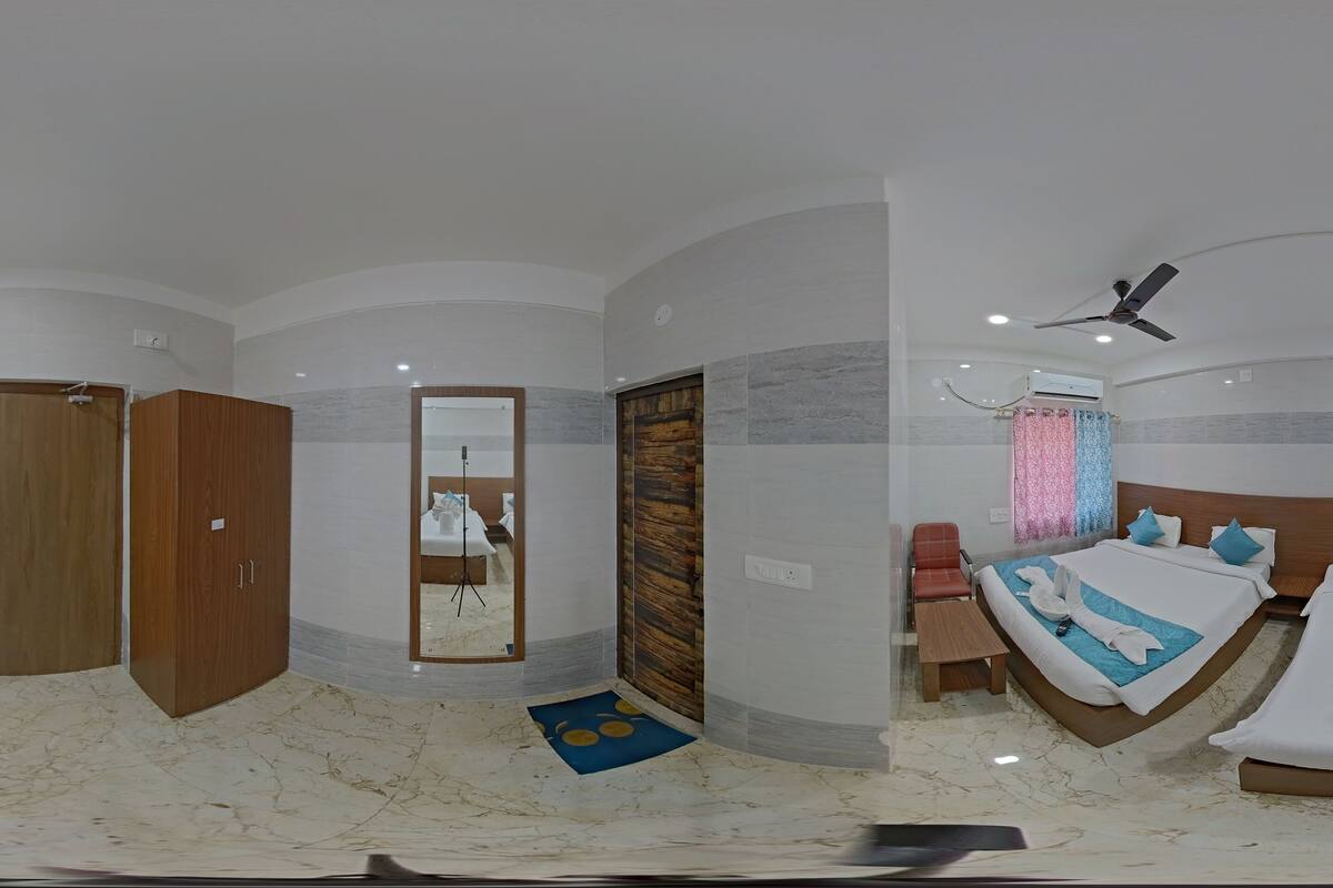 A modern hotel room with a curved ceiling, a large bed, a wooden wardrobe, a desk, and a TV mounted on the wall.