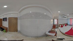 Une pièce spacieuse avec un plafond voûté, un lit avec une literie rouge, un bureau en bois et un climatiseur fixé au mur.