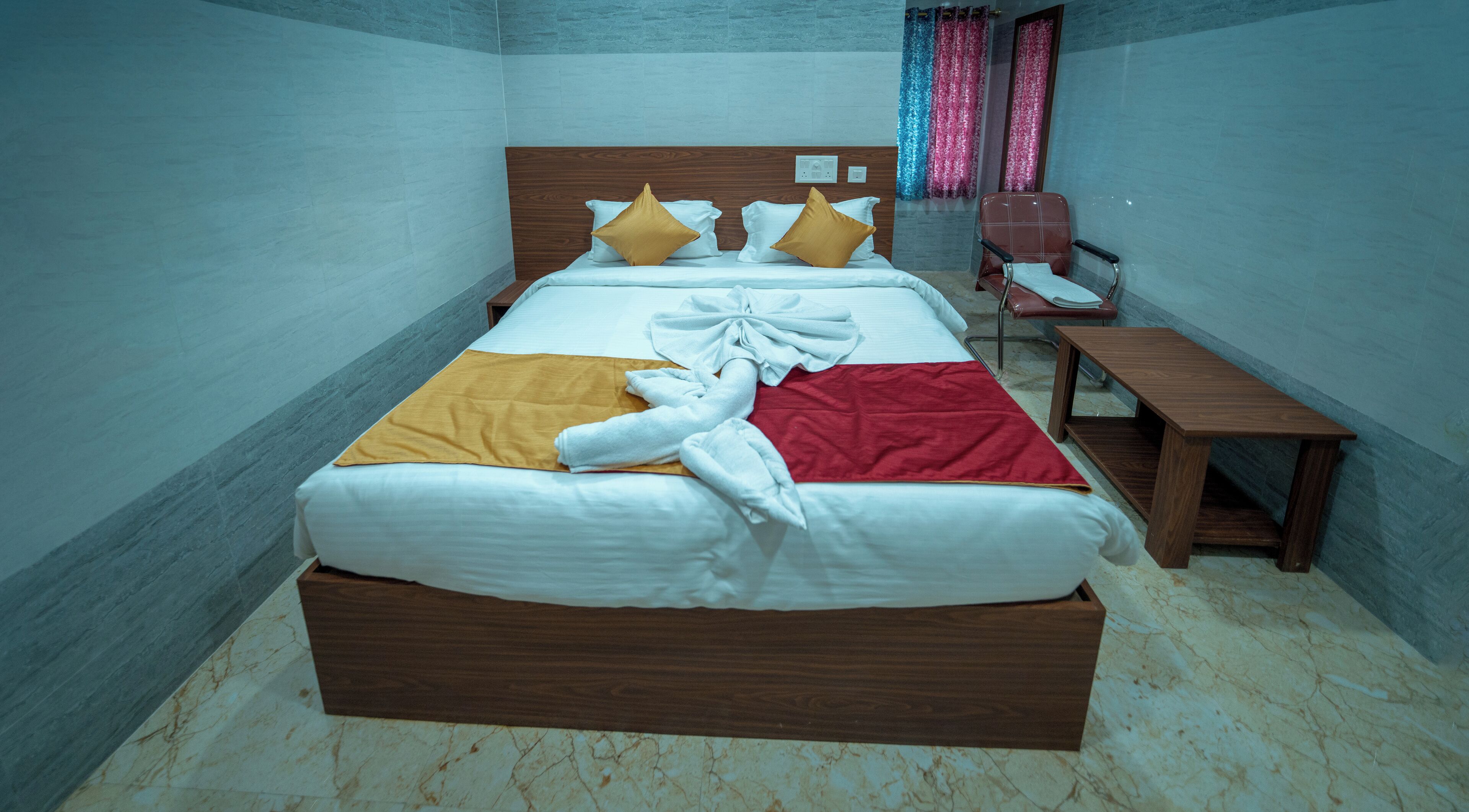 A neatly made bed with a wooden headboard, a bedside table, and a chair.