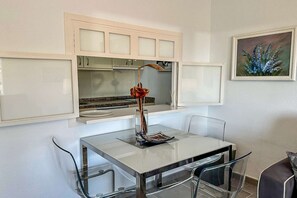 A modern kitchen with white cabinets, a glass dining table, and a unique rose-shaped light fixture.
