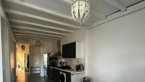 Une cuisine moderne avec un coin repas comprenant une table en verre et des chaises blanches.