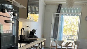 Een moderne keuken met roestvrijstalen apparatuur, een eetgedeelte met houten stoelen en een groot raam met uitzicht.