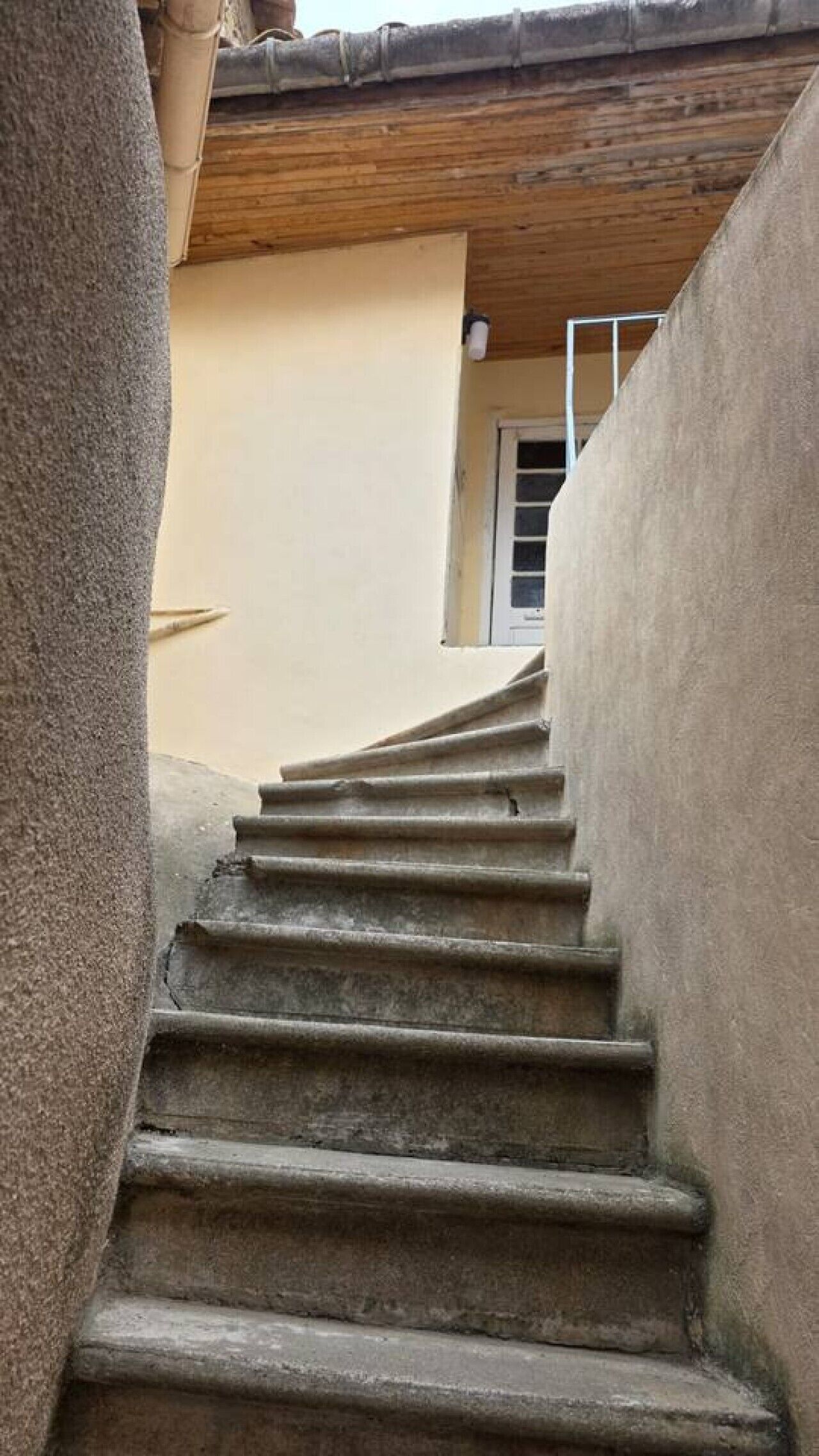 Eine Treppe aus Stein führt zu einer Tür mit einem Fenster darüber.