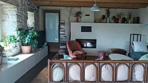 Ein gemütliches Wohnzimmer mit Kamin, einer Couch, einem Sessel und einem Bücherregal.