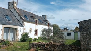 Ein weißes Haus mit geneigtem Dach, Steinmauern und einem kleinen Garten.