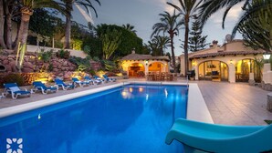 A swimming pool with lounge chairs, a patio area, and a building with arches.