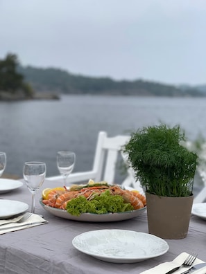 A table set with plates of seafood, a potted plant, and wine glasses.