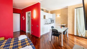 A compact hotel room with a bed, a dining area, and a kitchenette. - Charming Apartment Genova City View (Genoa)
