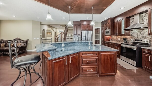 A spacious kitchen with a large island, wooden cabinets, stainless steel appliances, and pendant lighting. - Big Family & Group-Friendly 9BR Home in NW Calgary (Calgary)