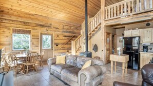 A wooden interior with a sofa, dining table, chairs, and a kitchen area.