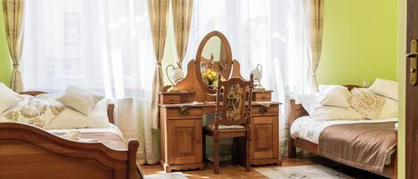 Un dormitorio con una cama de madera, un escritorio de madera con espejo y una araña.