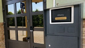 Une porte en métal noir avec un panneau en verre et un clavier pour ouvrir à l’aide d’un code.