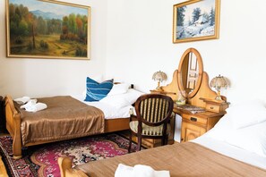 Une chambre d’hôtel avec deux lits, un bureau, une chaise, un miroir et deux tableaux au mur.