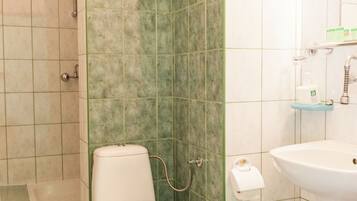 Une salle de bain comprenant des toilettes, un lavabo et un espace douche.