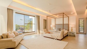 Ein modernes Schlafzimmer mit Himmelbett, einer Couch und großen Fenstern mit Blick ins Freie.
