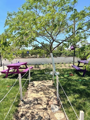 A picnic area with a stone pathway, picnic tables, and a tree.