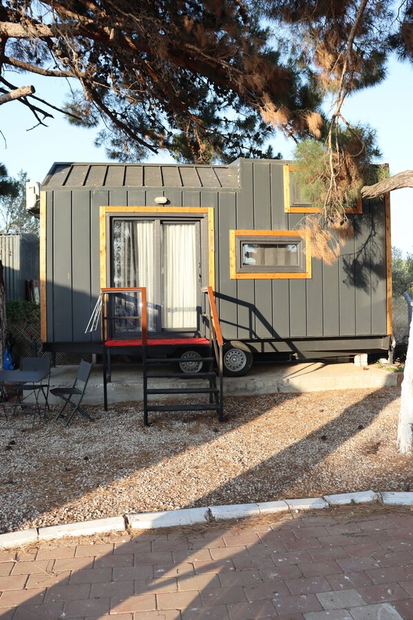 Une maison mobile avec un petit porche, une fenêtre et une porte.