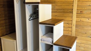 A white storage unit with multiple compartments and a wooden top shelf.