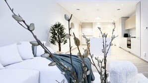 Un salon moderne avec un canapé blanc, une table basse et des branches décoratives.