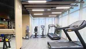 Une salle de sport équipée de tapis de course, d’un vélo d’appartement et d’un distributeur d’eau.
