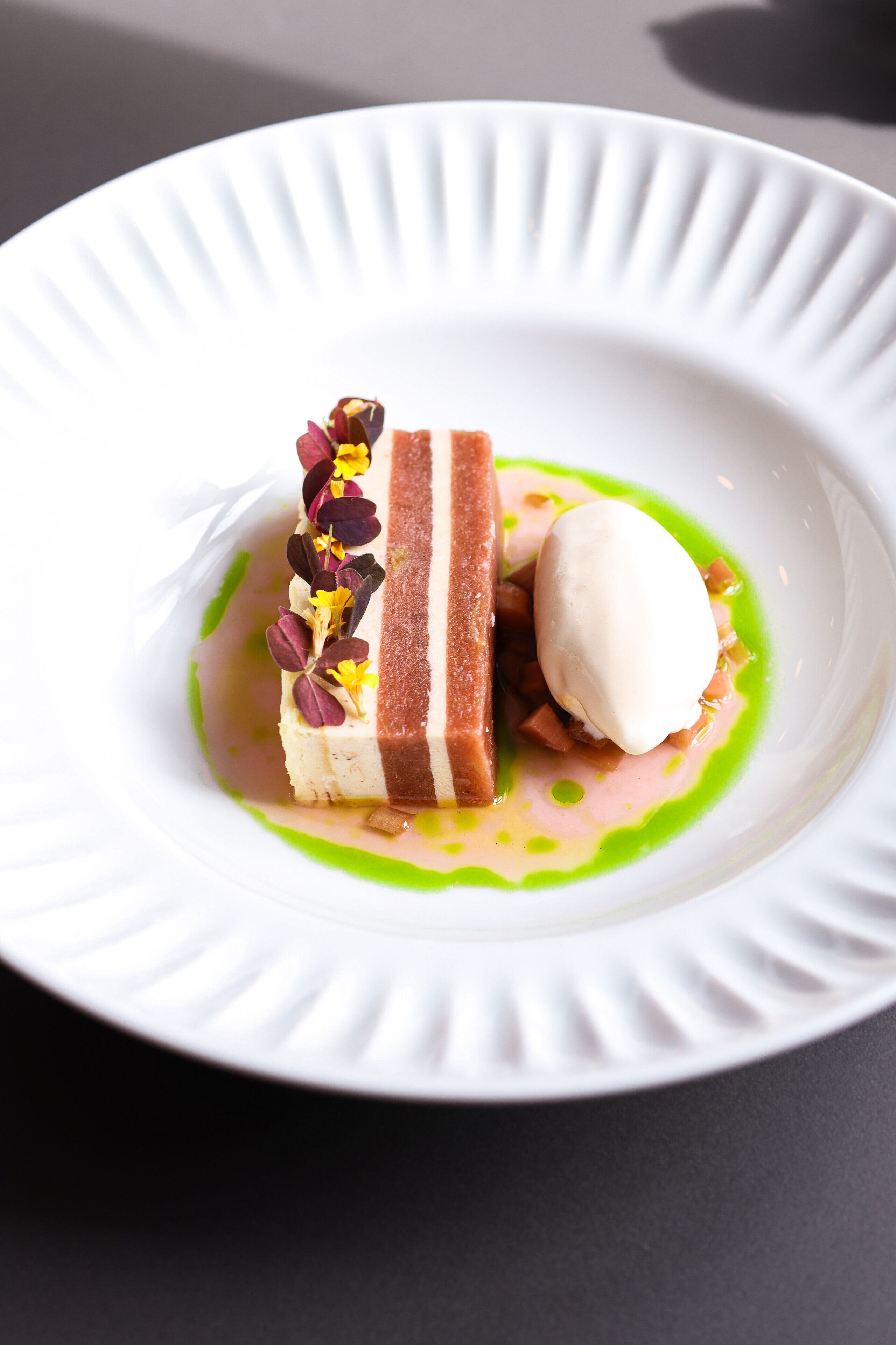 A dessert on a white plate with a green sauce and a white background.