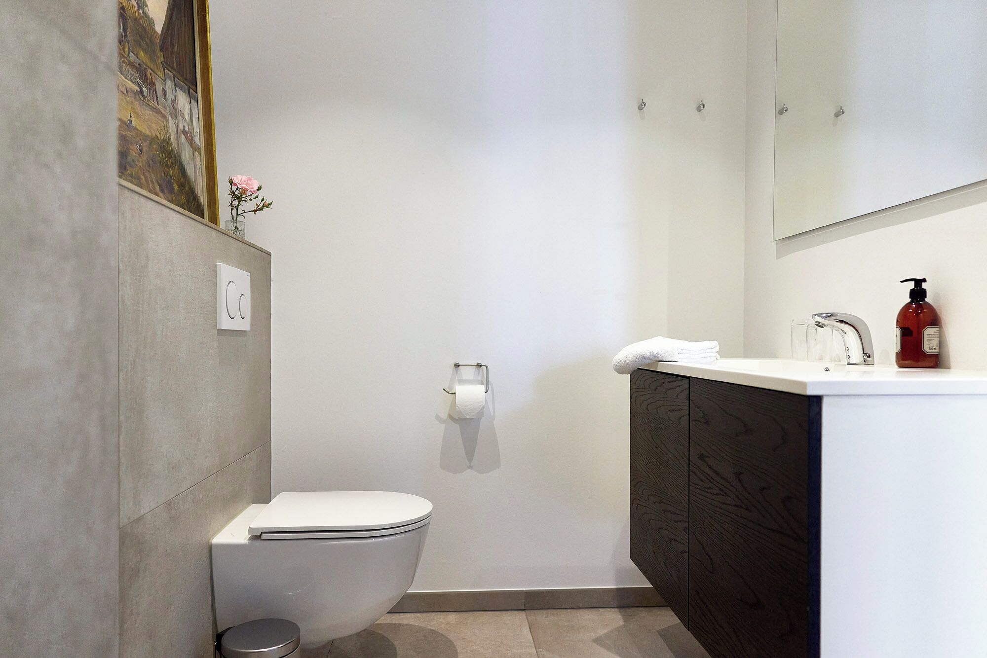 A modern bathroom with a toilet, a shower, and a sink.