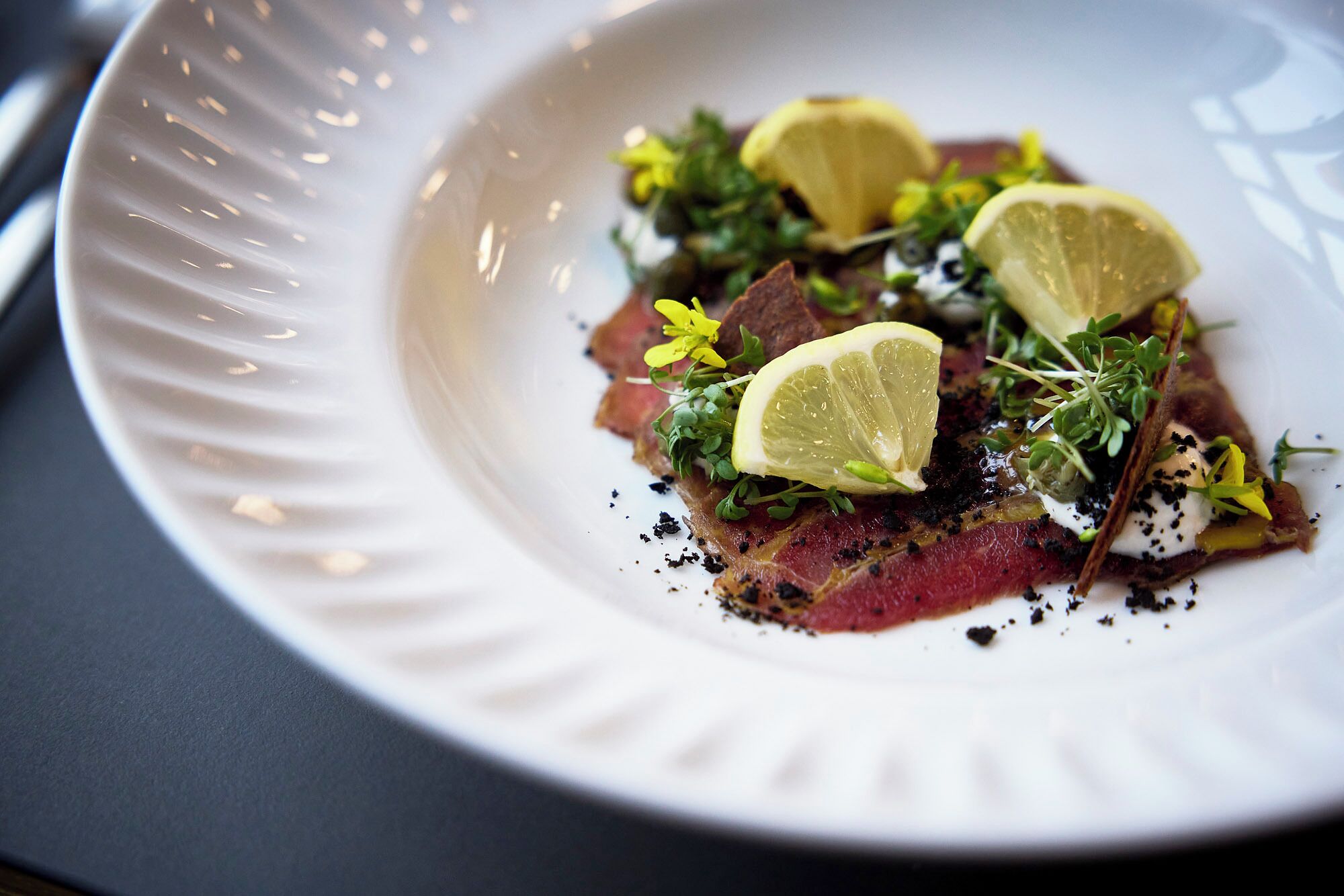 A white plate with a dish of food, garnished with lemon slices and herbs.