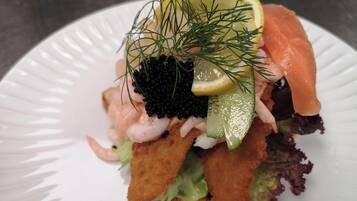 A seafood dish with shrimp, salmon, caviar, and garnishes on a white plate.