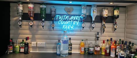 A bar area with a neon sign reading 'TWAIN AYE'S COUNTRY PARK' and various liquor bottles.