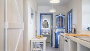 Una cocina estrecha con armarios blancos y azules, una isla central e iluminación colgante.