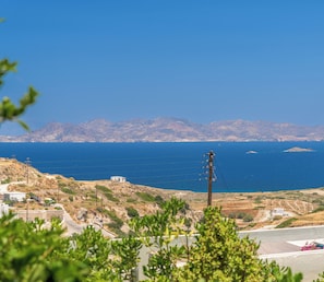 A coastal landscape with a clear view of the sea, a small island, and distant mountains.