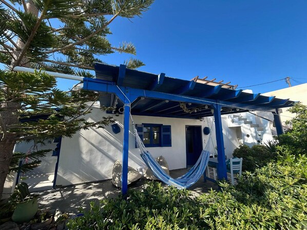 A white building with blue accents, a hammock, and lush greenery. - Mediterranea Blu (Milos)