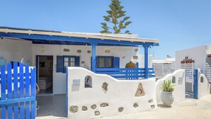 Un edificio con fachada azul y blanca, una puerta y una maceta.