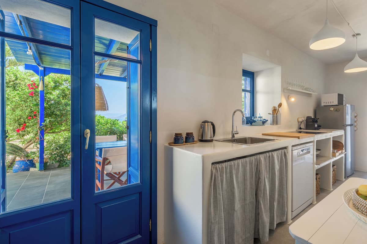 A modern kitchen with a large window, white countertops, and a built-in dishwasher.