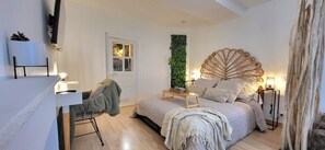 A bedroom with a bed, bedside tables, a desk, a chair, a window with a view, and a wall-mounted plant. - Le Palma Studio in the City Center   (Rennes)