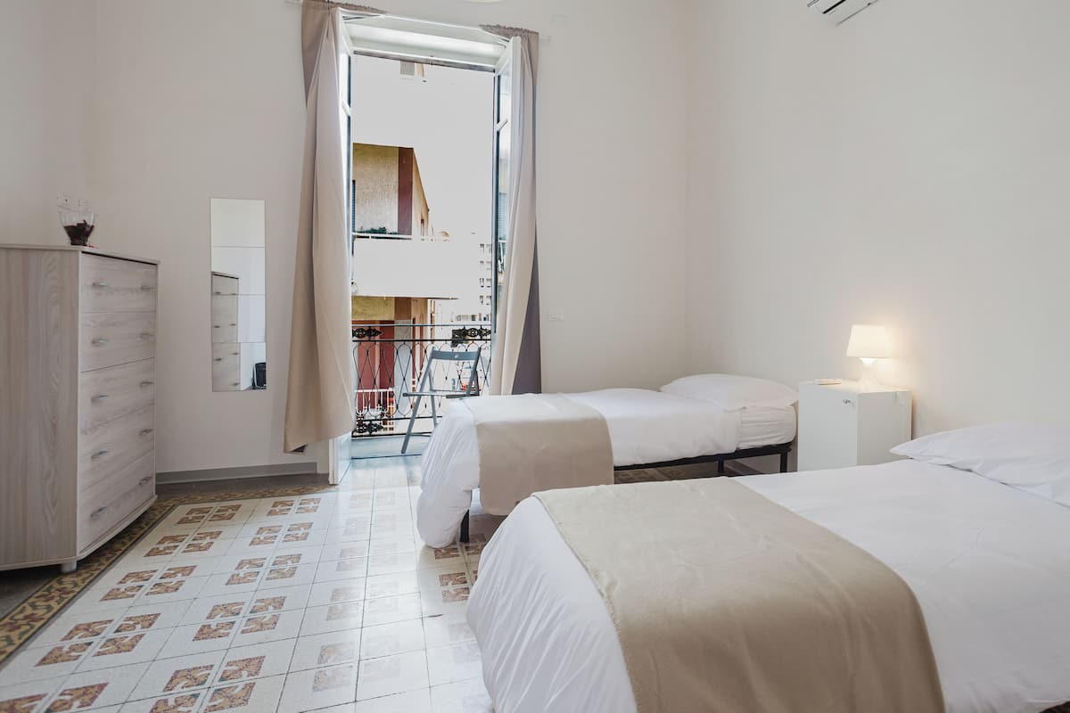 A hotel room with two beds, a dresser, and a balcony with a view.