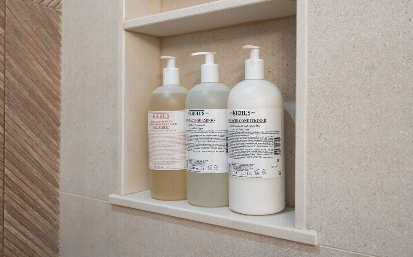 Three bottles of Kiehl's products on a shelf.
