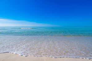 Ein Strand mit klarem, blauem Wasser und einem sandigen Ufer.