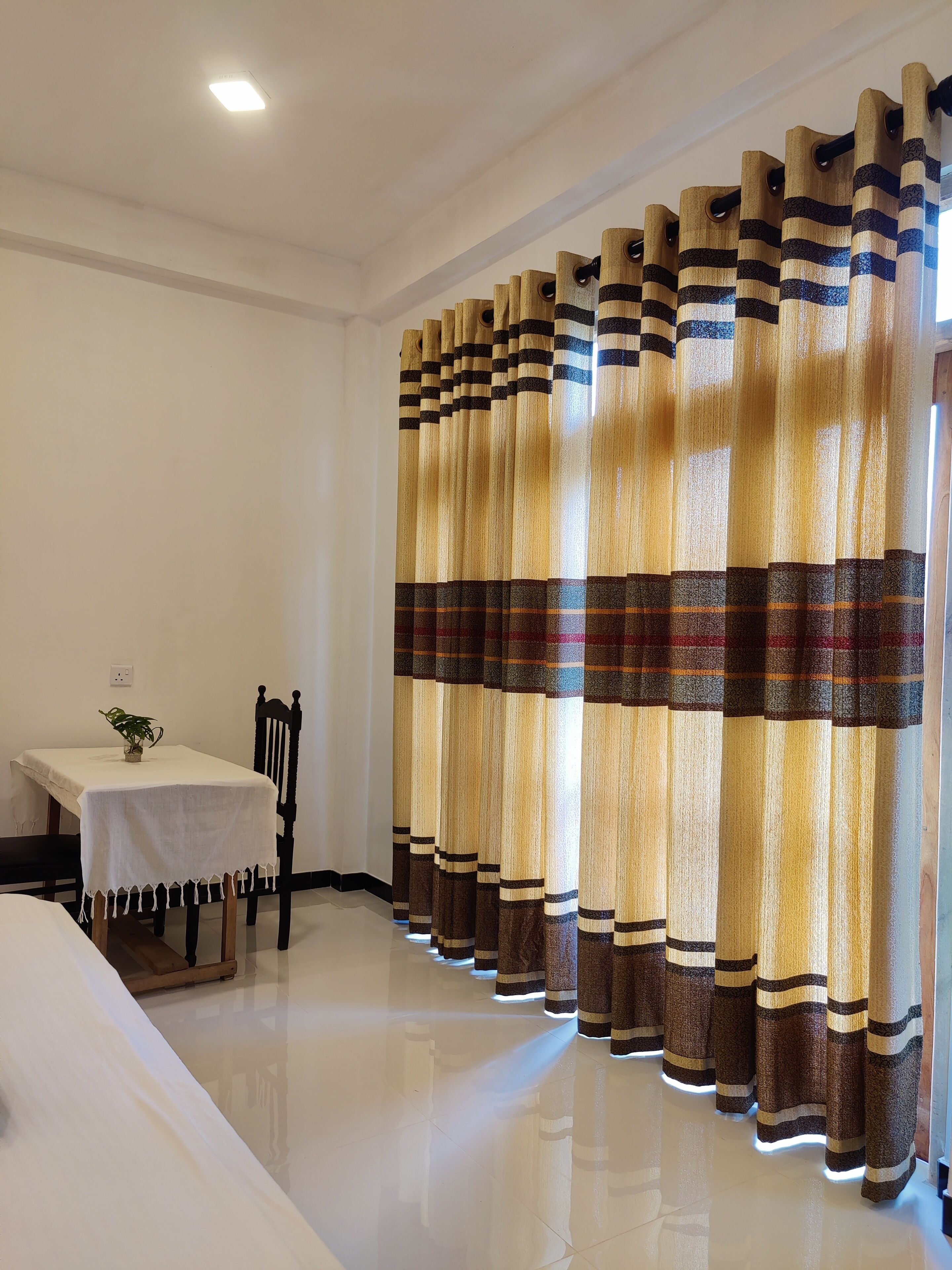 A room with a dining table, chairs, and a curtain with a striped pattern.