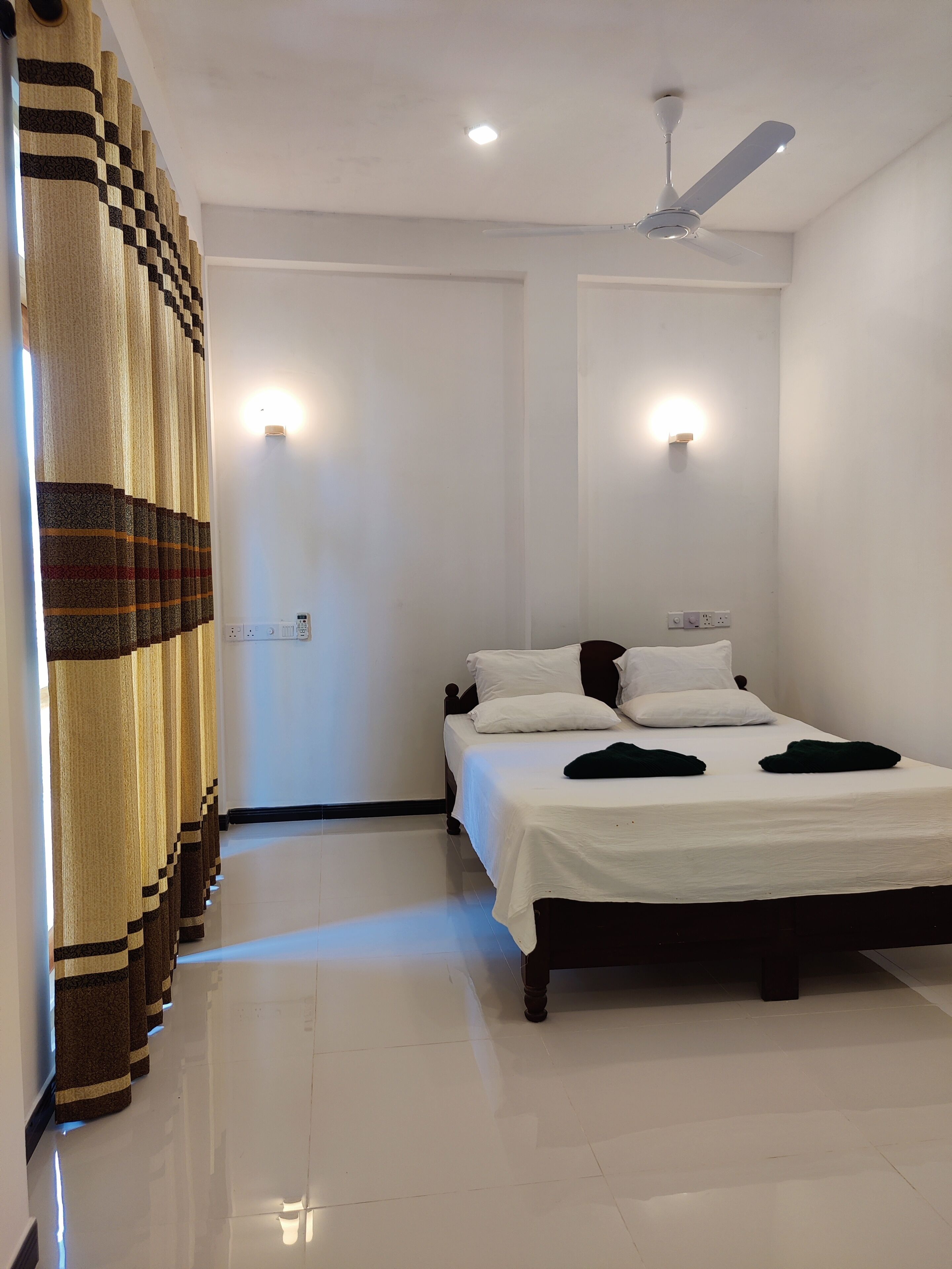 Un dormitorio con cama, ventilador de techo y una lámpara de pared.