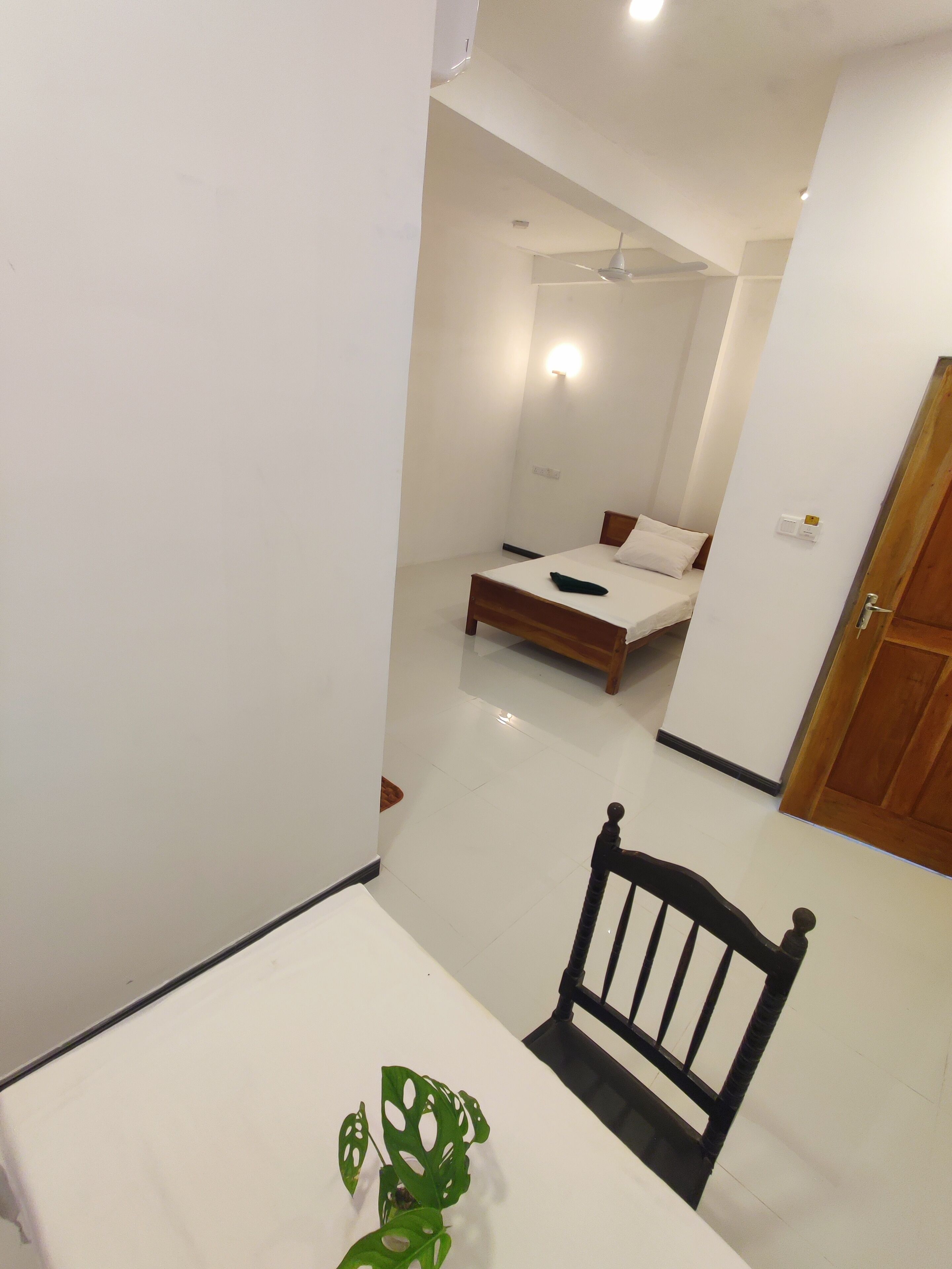 A room with a bed, a chair, and a table with a plant.