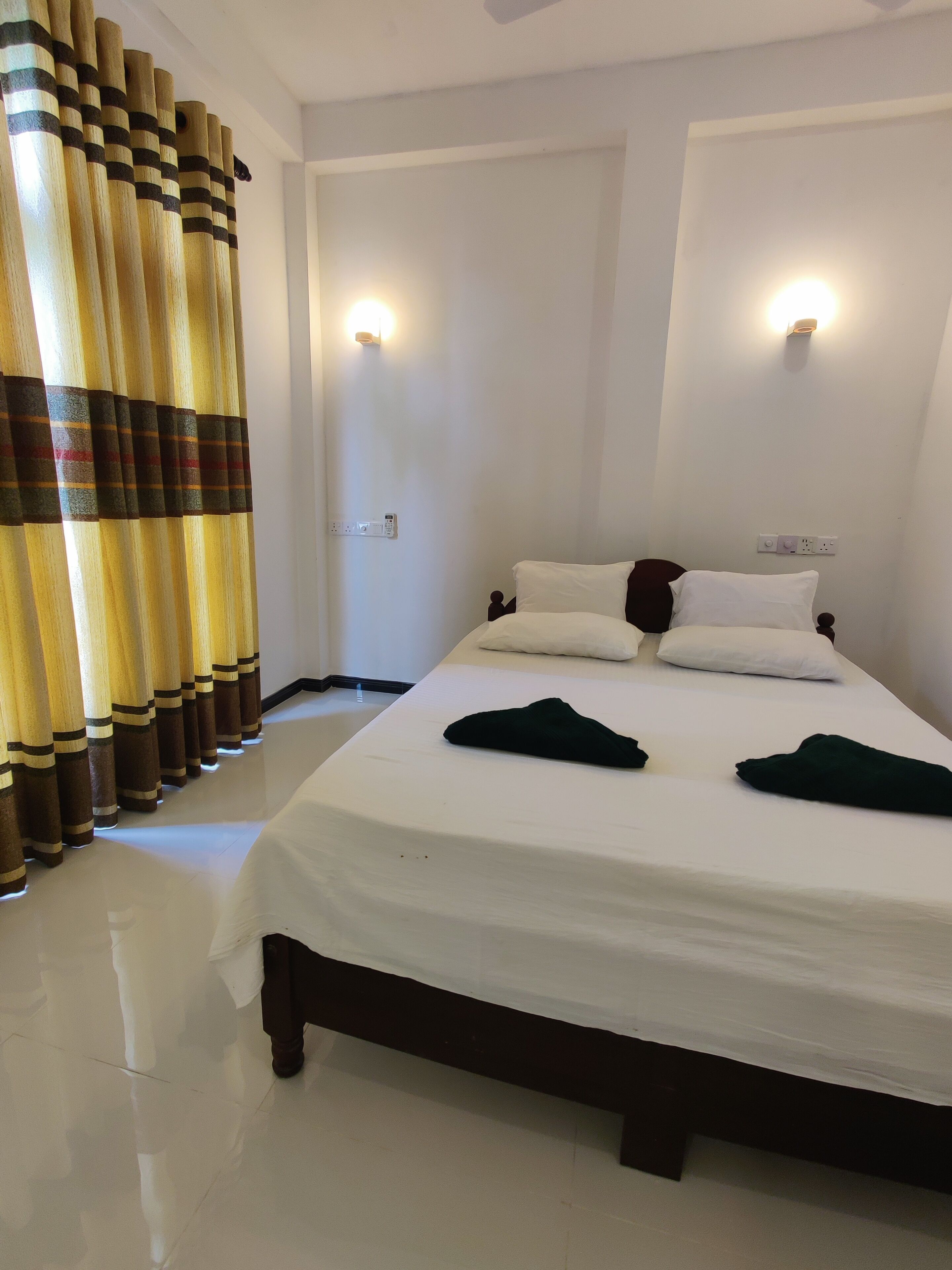A hotel room with a large bed, two bedside tables, and a wall-mounted light fixture.