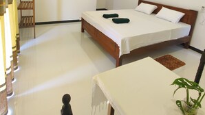 A bedroom with a wooden bed, white walls, a ceiling fan, and a small table with a plant. - Randi Guest House (Mirissa)