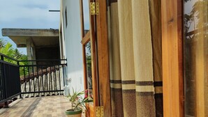 A wooden-floored balcony with a potted plant and a curtain. - Randi Guest House (Mirissa)