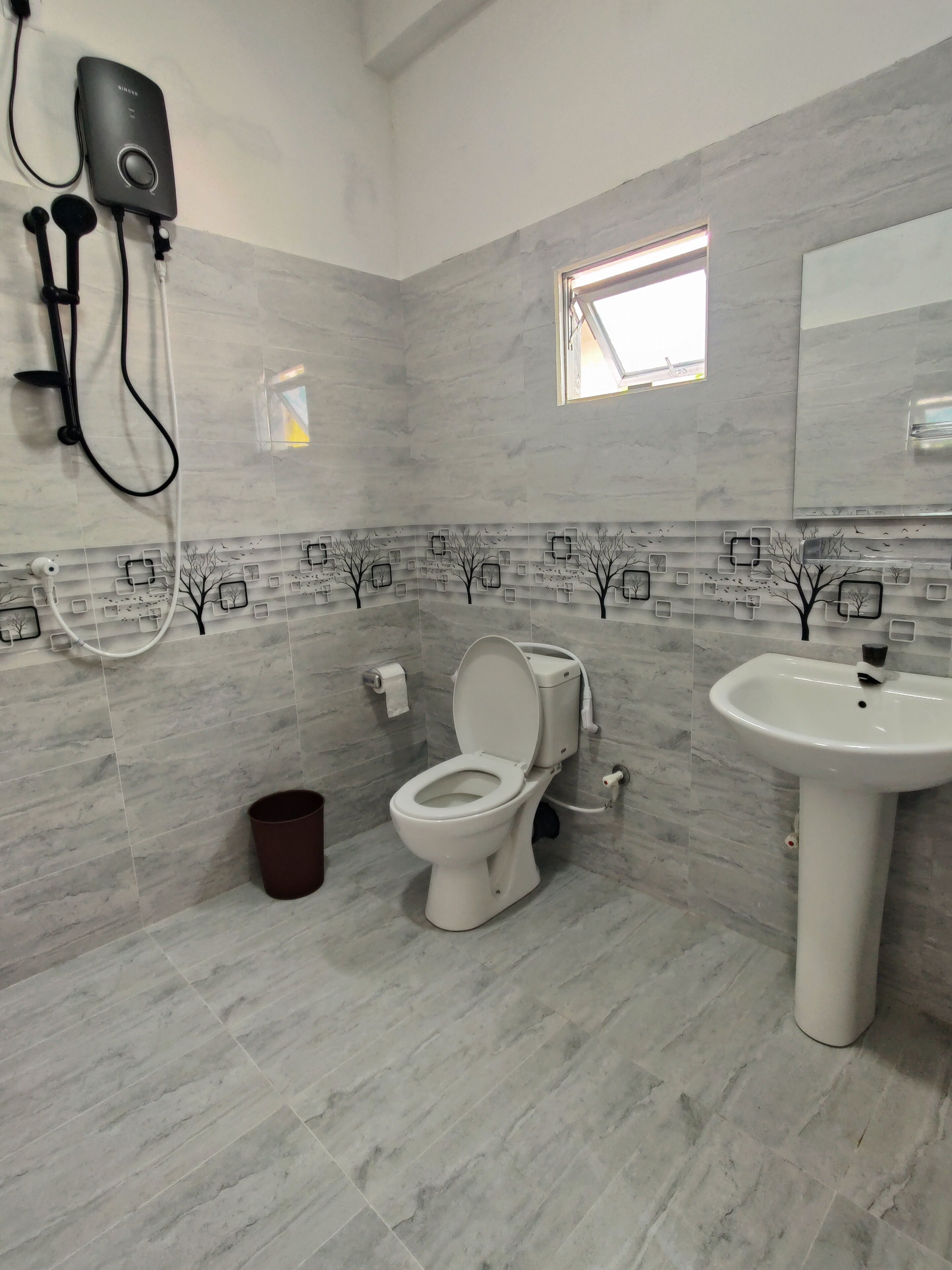 Ein modernes Badezimmer mit Toilette, Waschbecken und einer an der Wand befestigten Duschbrause.