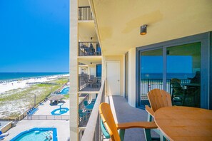 Un balcon avec vue sur la plage et l’océan, une piscine et un espace salon extérieur.