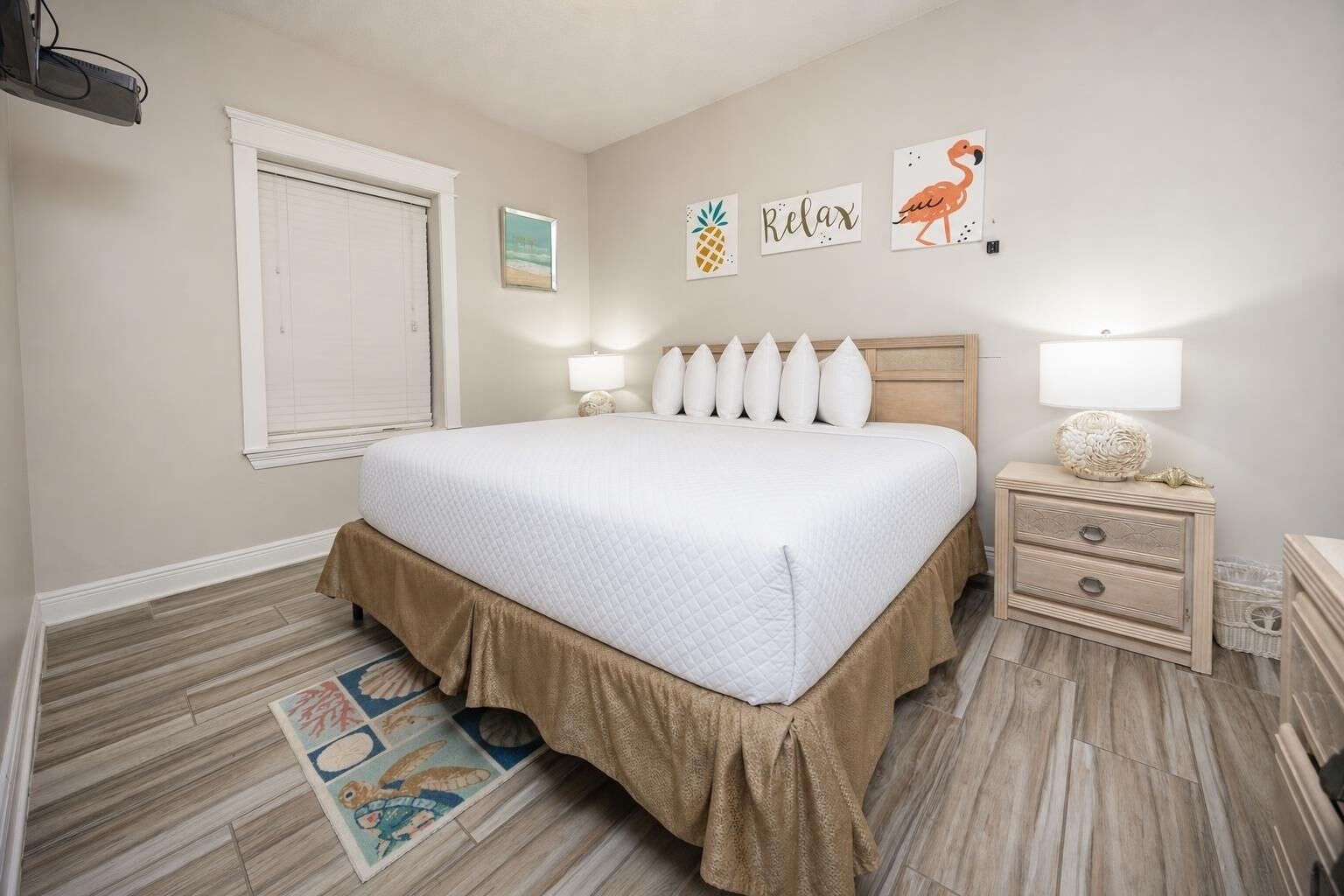 Ein Schlafzimmer mit einem Bett, Nachttischen, einer Fensterbank und Wandbildern.